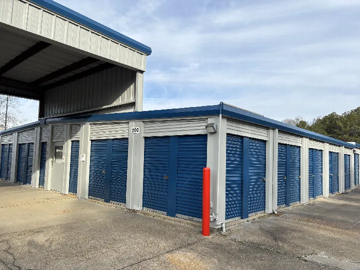 Self-storage building with gray metal panels, blue doors, and blue roof trim