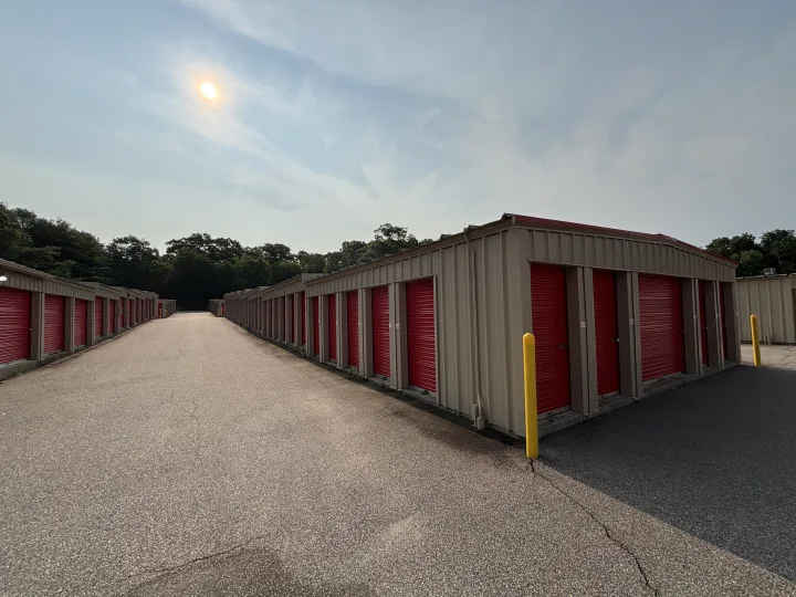 Self-storage buildings with red roll-up doors and light-colored walls