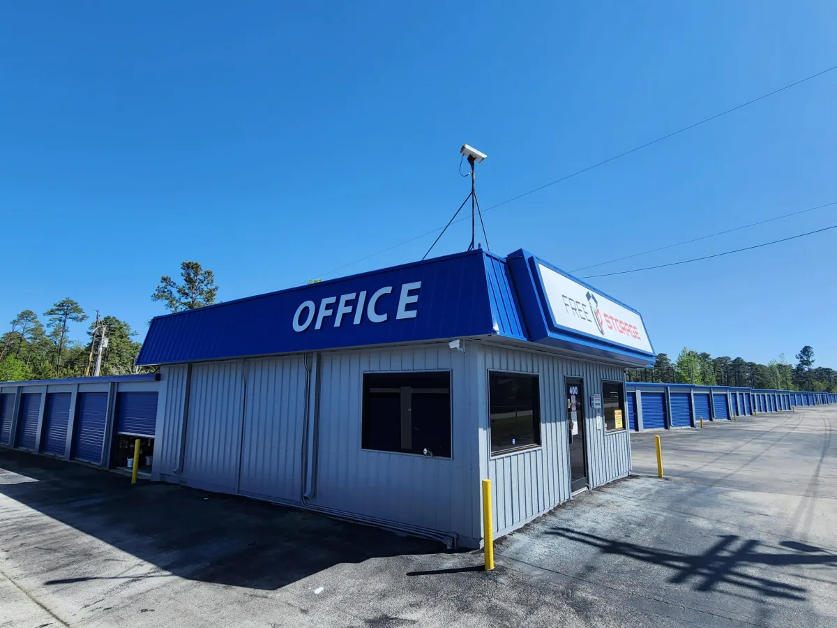 Blue and gray self-storage office building beside rows of blue storage doors