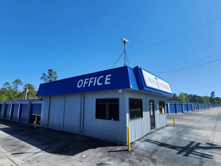 Blue and gray self-storage office building beside rows of blue storage doors